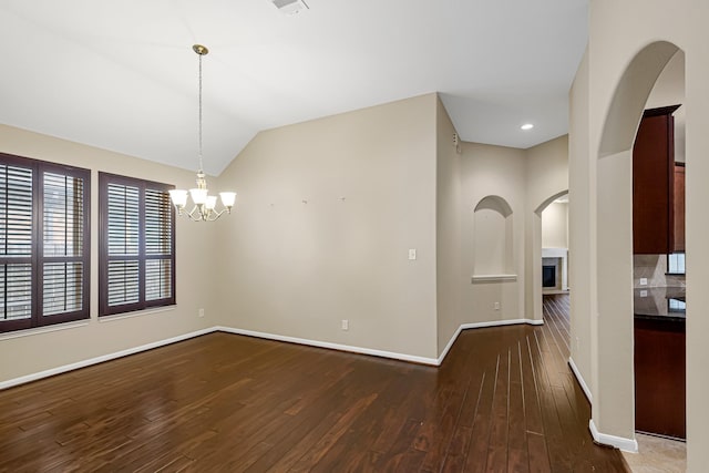 unfurnished room featuring a notable chandelier, lofted ceiling, and dark hardwood / wood-style floors