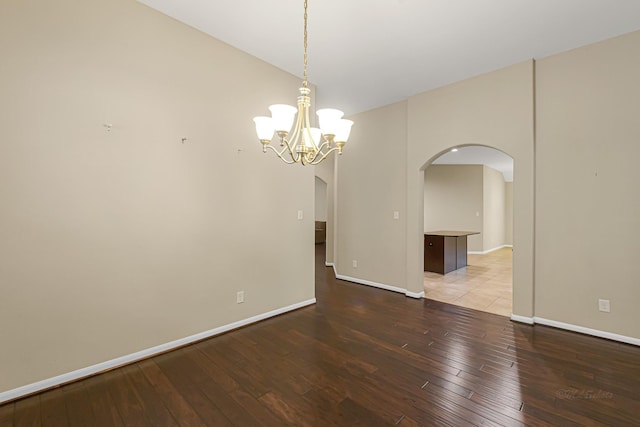 unfurnished room with hardwood / wood-style floors and an inviting chandelier