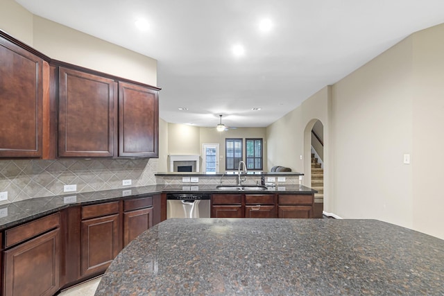 kitchen featuring stainless steel dishwasher, dark stone countertops, tasteful backsplash, and sink