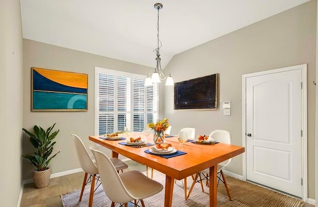 dining space featuring lofted ceiling, wood-type flooring, and an inviting chandelier