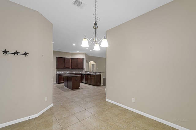 kitchen featuring a chandelier, hanging light fixtures, a kitchen island, dark brown cabinets, and light tile patterned flooring