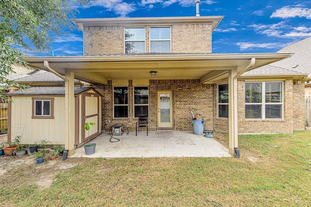 rear view of property with a yard, a storage unit, and a patio