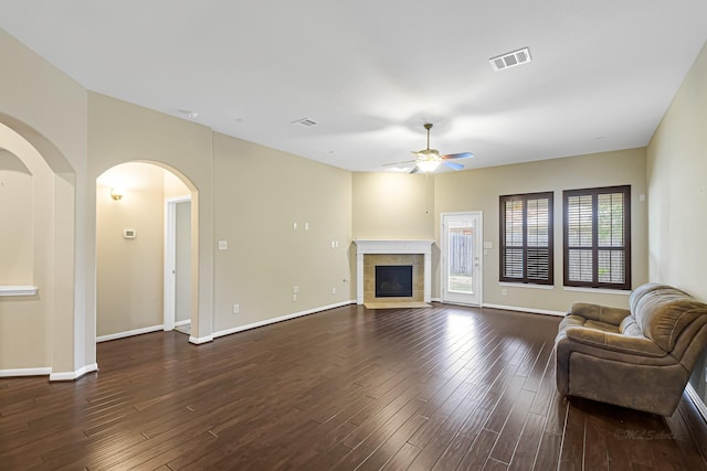 living room with a tile fireplace, ceiling fan, and dark hardwood / wood-style floors