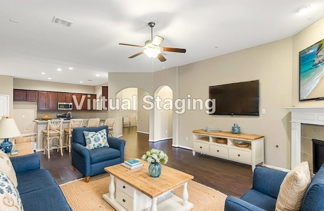 living room featuring dark hardwood / wood-style flooring, ceiling fan, and a tile fireplace