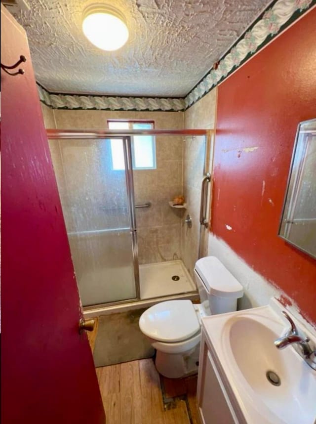 full bathroom with a textured ceiling, toilet, vanity, and wood-type flooring