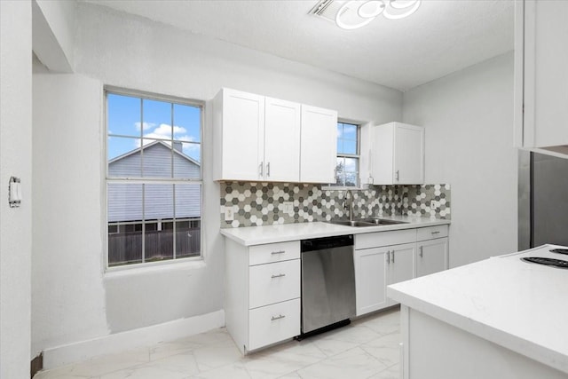 kitchen featuring a wealth of natural light, sink, white cabinetry, stainless steel dishwasher, and tasteful backsplash