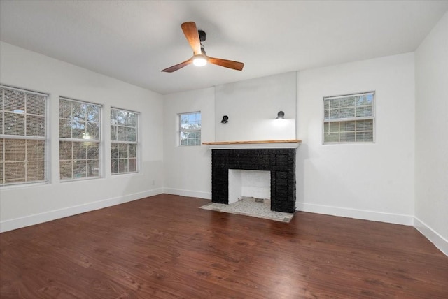 unfurnished living room featuring a fireplace, dark wood-type flooring, and ceiling fan