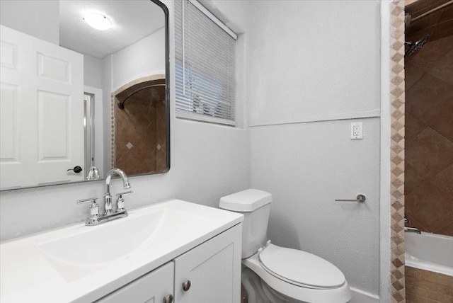 full bathroom with tiled shower / bath, vanity, and toilet