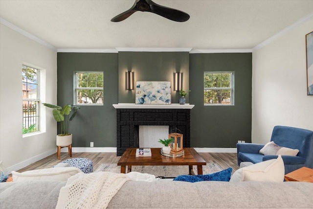 living room featuring a brick fireplace, ornamental molding, ceiling fan, and light hardwood / wood-style flooring