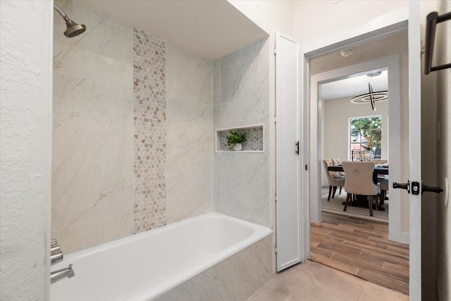 bathroom featuring an inviting chandelier and tiled shower / bath