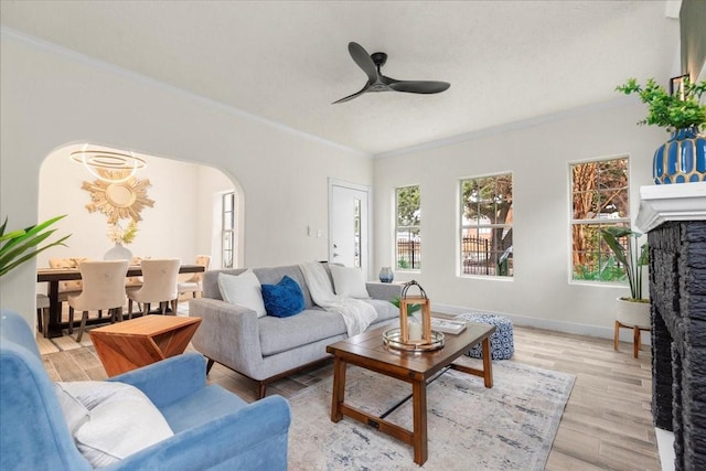 living room with a fireplace, ceiling fan, light hardwood / wood-style floors, and ornamental molding