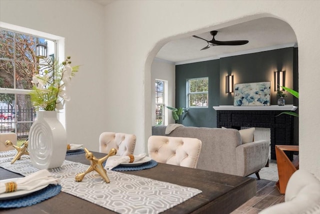 dining space with a brick fireplace, ceiling fan, plenty of natural light, and ornamental molding