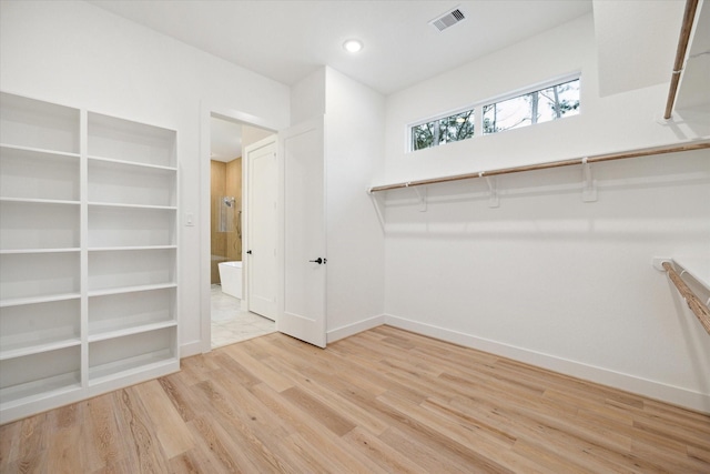 walk in closet with light hardwood / wood-style floors