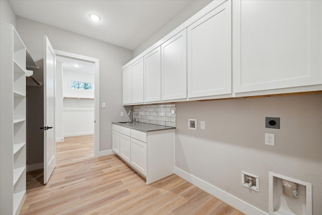 laundry area featuring sink, hookup for a washing machine, light hardwood / wood-style flooring, hookup for an electric dryer, and cabinets