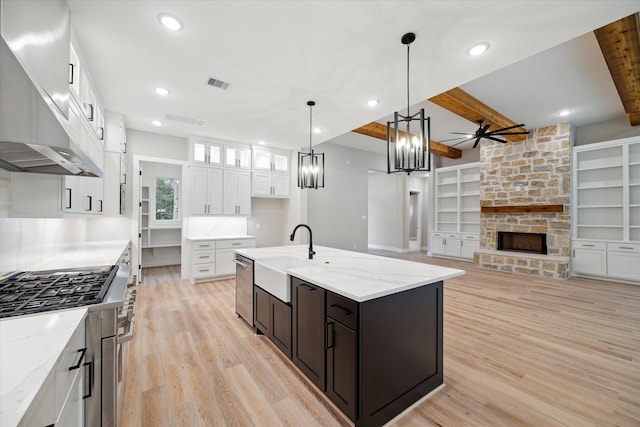 kitchen with white cabinets, an island with sink, sink, built in features, and ceiling fan