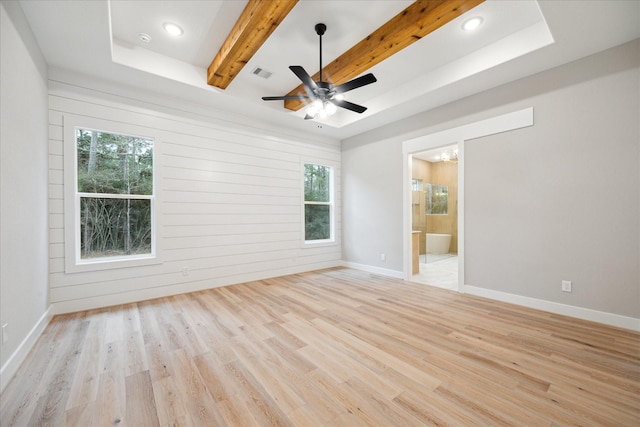 spare room featuring light hardwood / wood-style floors, wooden walls, ceiling fan, a tray ceiling, and beamed ceiling