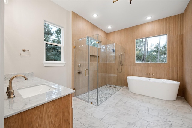 bathroom with independent shower and bath, plenty of natural light, and vanity