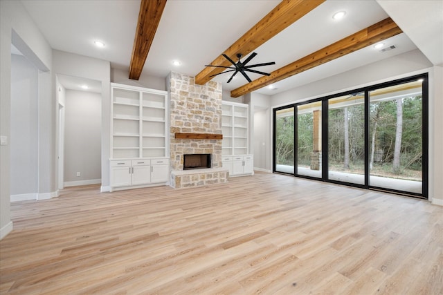 unfurnished living room featuring a stone fireplace, ceiling fan, beam ceiling, light hardwood / wood-style flooring, and built in shelves