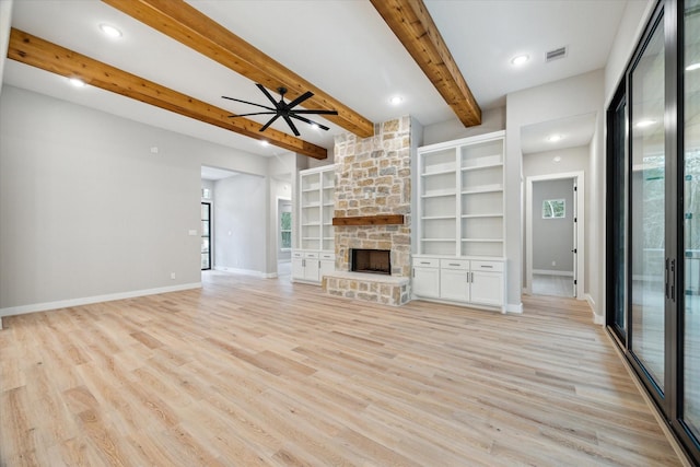 unfurnished living room with a fireplace, built in features, light wood-type flooring, ceiling fan, and beam ceiling