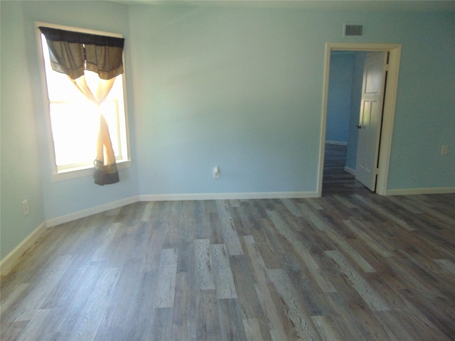 unfurnished room featuring wood finished floors, baseboards, and visible vents