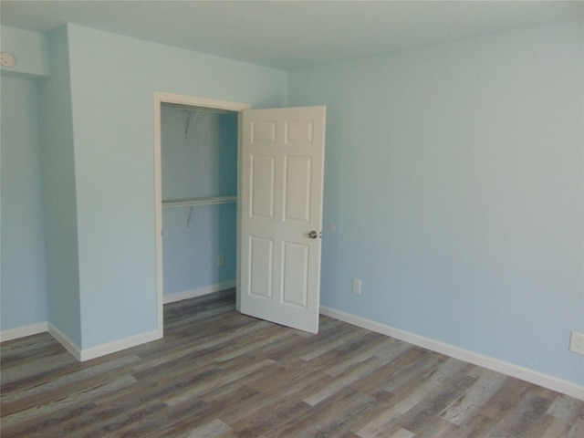 unfurnished bedroom with a closet, baseboards, and wood finished floors