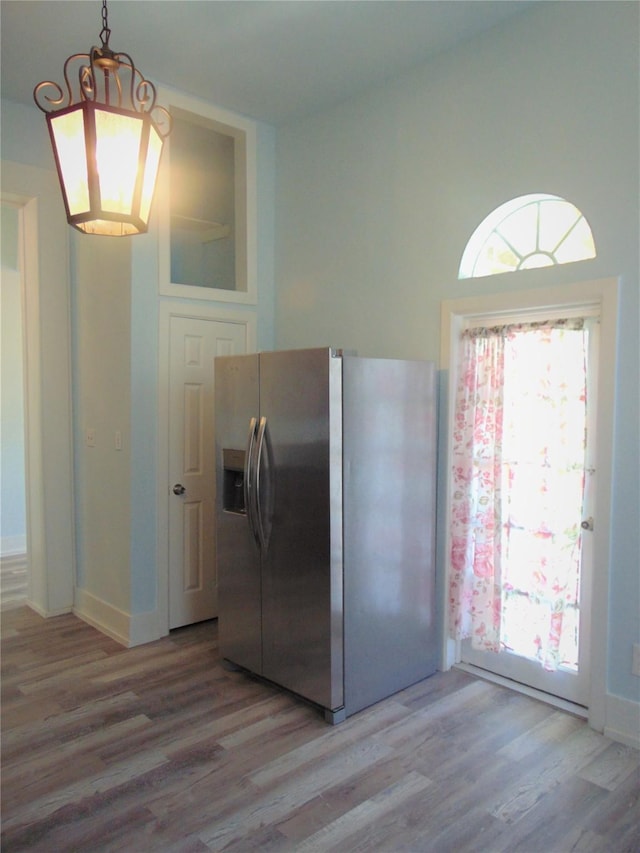 kitchen featuring stainless steel refrigerator with ice dispenser, decorative light fixtures, and light wood-type flooring