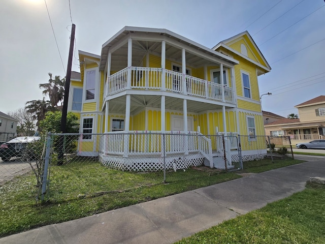 view of front facade featuring a balcony, a porch, a front lawn, and fence