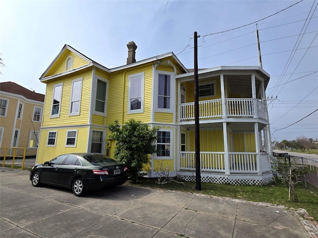 view of front of home featuring a balcony, a porch, and driveway