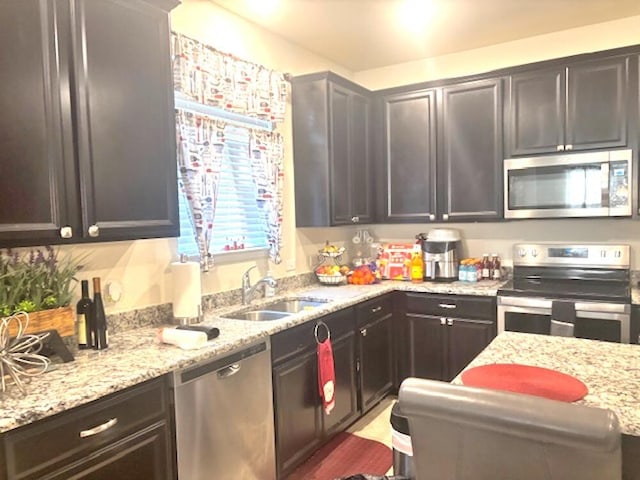 kitchen with stainless steel appliances, sink, dark brown cabinets, and light stone countertops