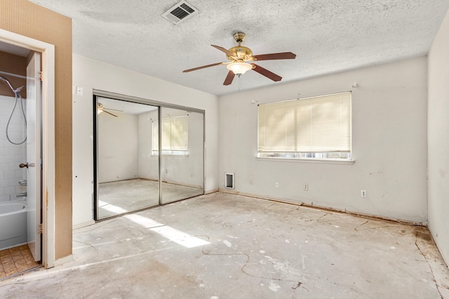 unfurnished bedroom featuring ceiling fan, a closet, ensuite bathroom, and a textured ceiling