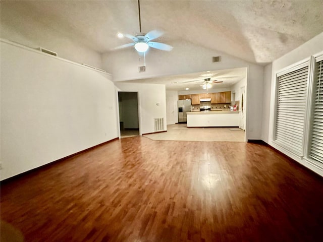 unfurnished living room featuring lofted ceiling, ceiling fan, and light hardwood / wood-style flooring