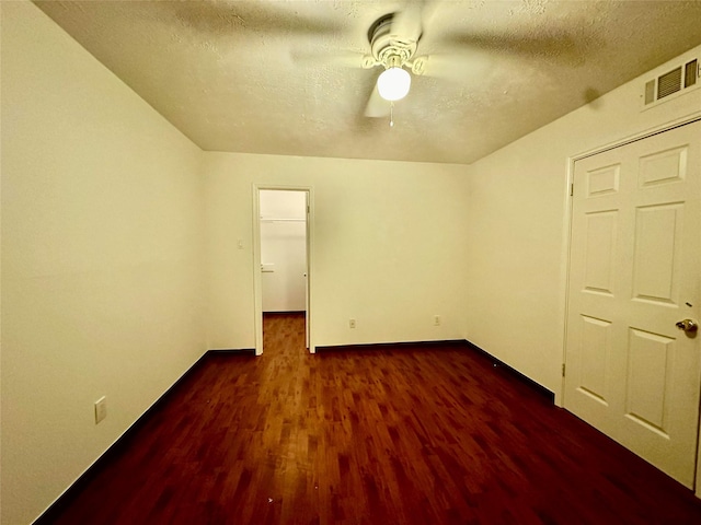 unfurnished bedroom with ceiling fan, dark wood-type flooring, and a textured ceiling