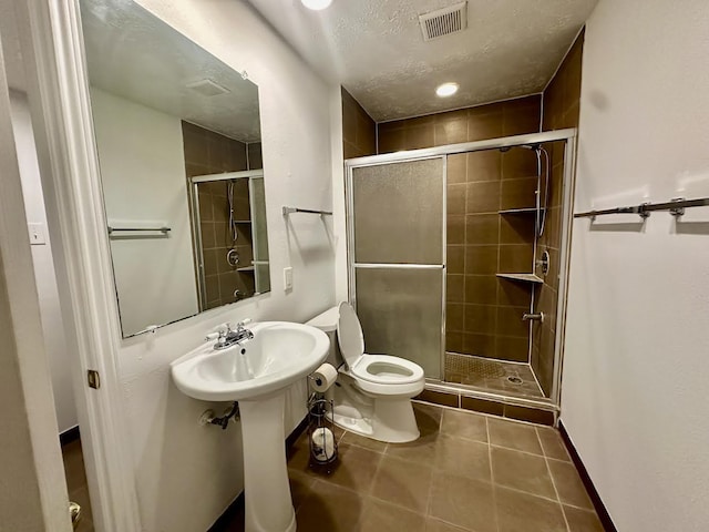 bathroom featuring toilet, an enclosed shower, tile patterned floors, and a textured ceiling