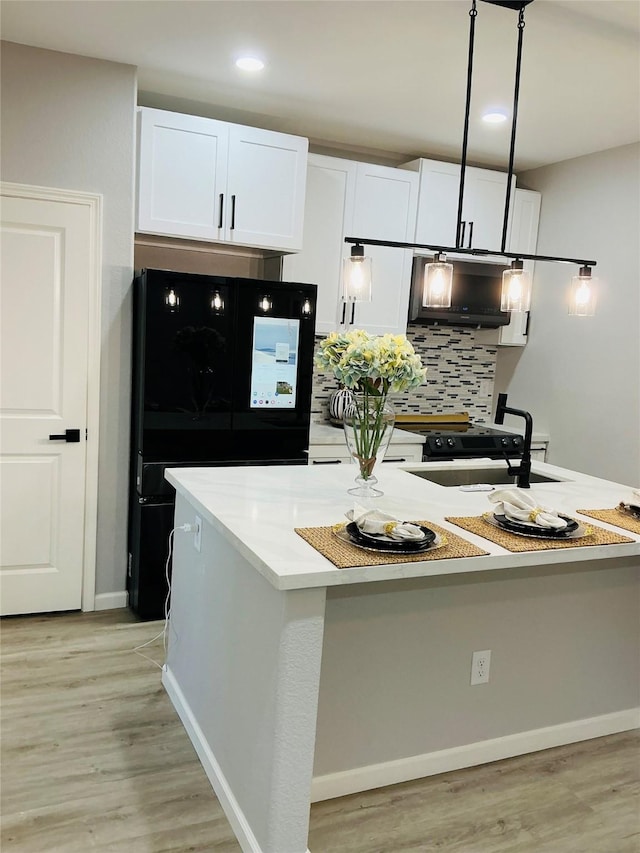 kitchen featuring black fridge, white cabinets, sink, and light hardwood / wood-style floors