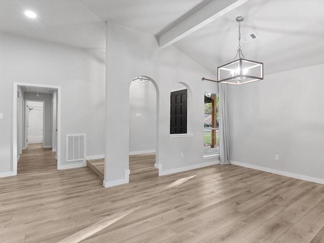 spare room featuring light wood-type flooring, a chandelier, and vaulted ceiling with beams