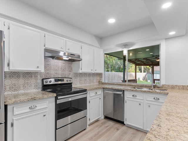 kitchen with light hardwood / wood-style flooring, tasteful backsplash, white cabinets, appliances with stainless steel finishes, and sink