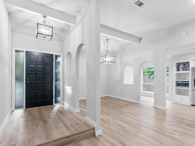 entrance foyer with an inviting chandelier, lofted ceiling with beams, and light hardwood / wood-style floors