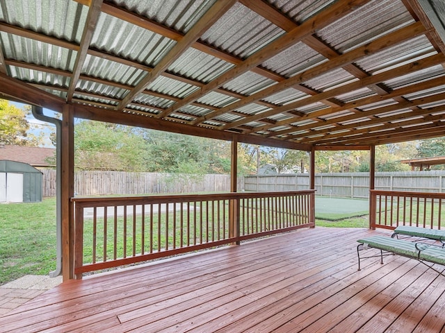 wooden deck with a storage unit and a lawn