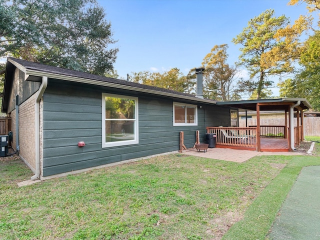 rear view of property with a lawn, a patio area, and a wooden deck