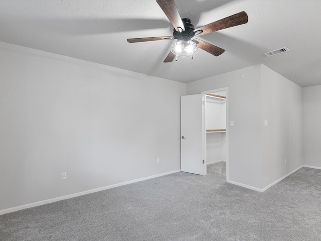 unfurnished bedroom with carpet flooring, a walk in closet, ceiling fan, and a closet