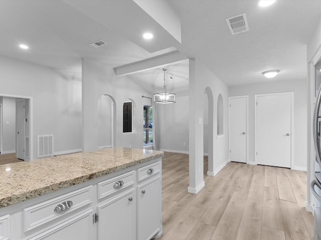 kitchen with light stone countertops, lofted ceiling with beams, hanging light fixtures, light hardwood / wood-style floors, and white cabinets