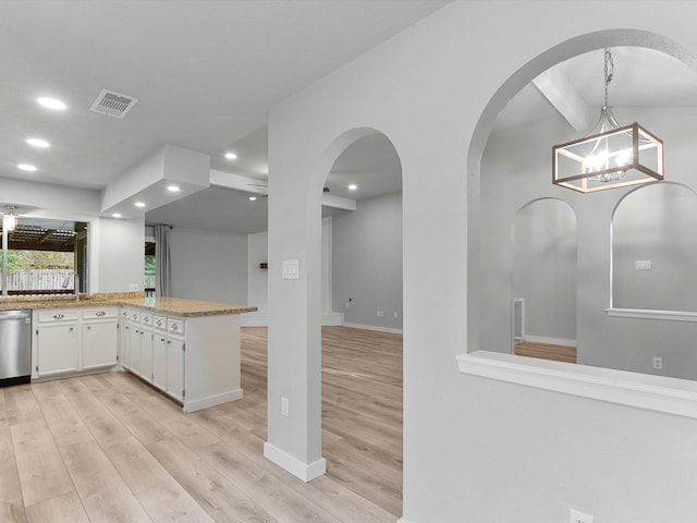 kitchen featuring kitchen peninsula, dishwasher, pendant lighting, light wood-type flooring, and white cabinetry