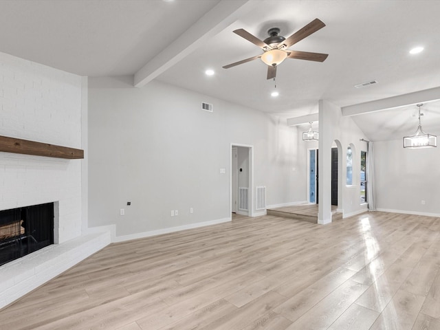 unfurnished living room featuring ceiling fan, light hardwood / wood-style floors, a brick fireplace, and vaulted ceiling with beams