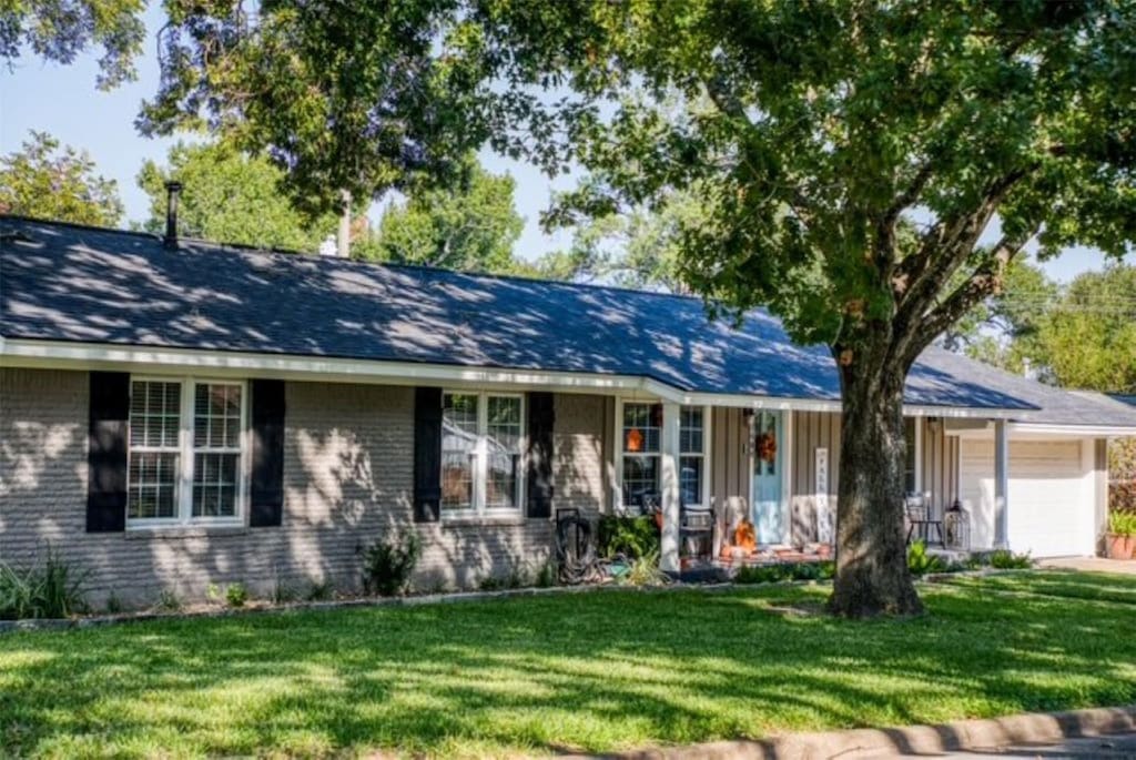 ranch-style home with a front lawn, a garage, and covered porch