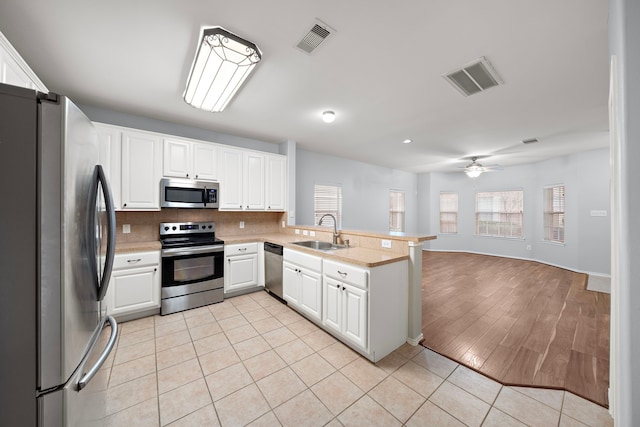 kitchen with sink, white cabinetry, ceiling fan, kitchen peninsula, and appliances with stainless steel finishes