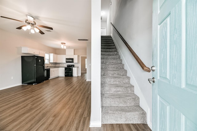 stairway with ceiling fan and wood-type flooring