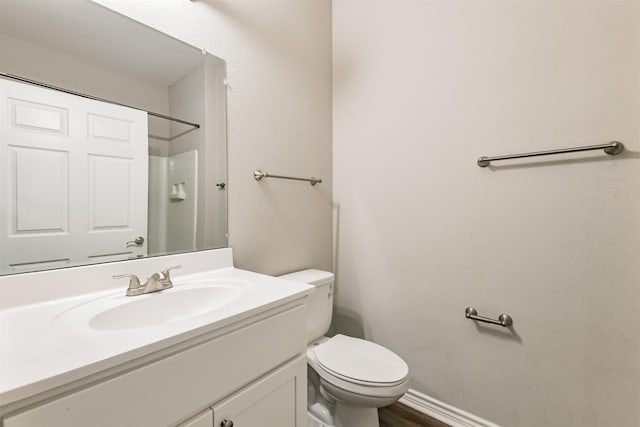 bathroom featuring toilet, walk in shower, and vanity