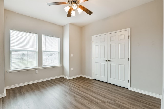 unfurnished bedroom with ceiling fan, dark wood-type flooring, and a closet