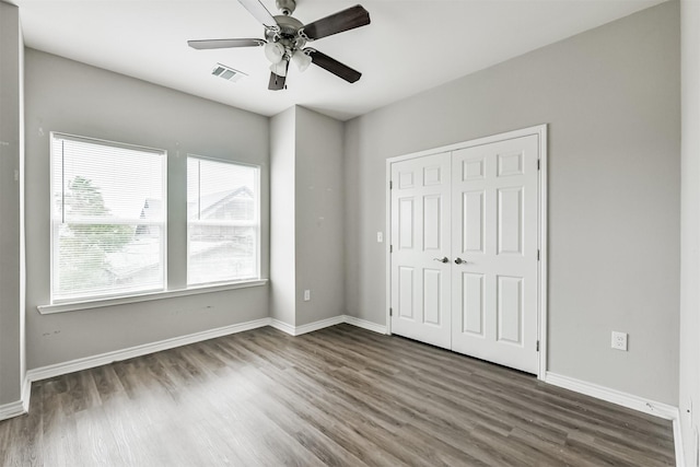 unfurnished bedroom featuring ceiling fan, dark wood-type flooring, and a closet