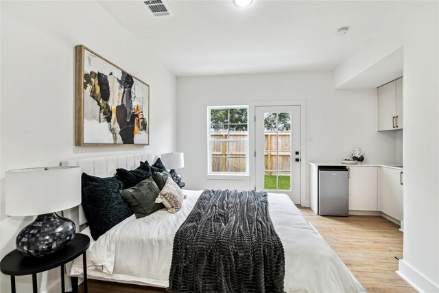 bedroom with light hardwood / wood-style floors and stainless steel refrigerator